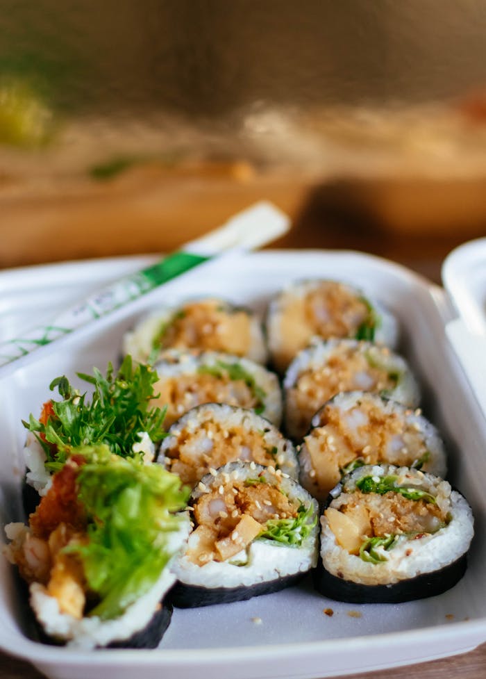 About Appetizing sushi rolls in a takeaway box, perfect for a fresh and healthy meal.