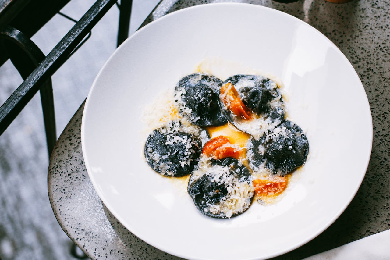 Delicious black ravioli served with cheese and tomatoes in a sophisticated plating.